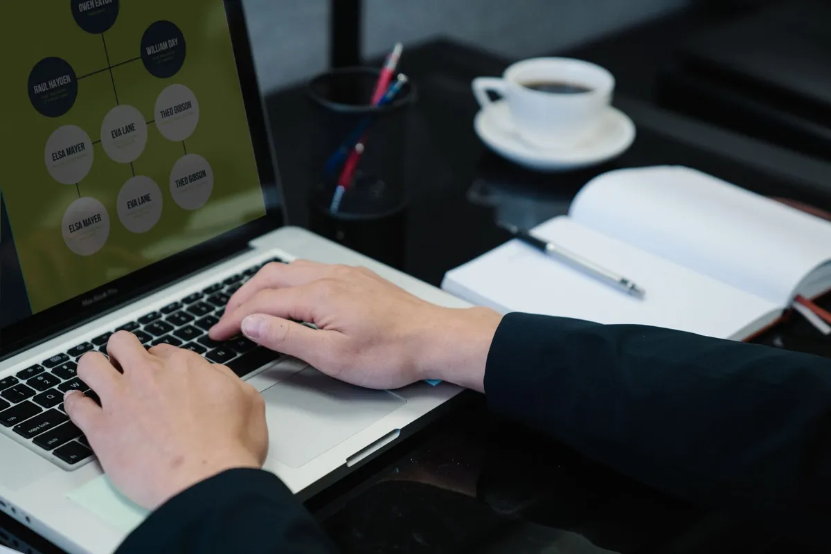 Professional typing on a laptop showing an org chart diagram