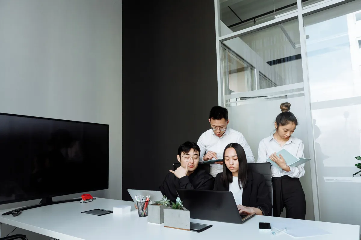 Asian colleagues reviewing AI-drafted work on a laptop