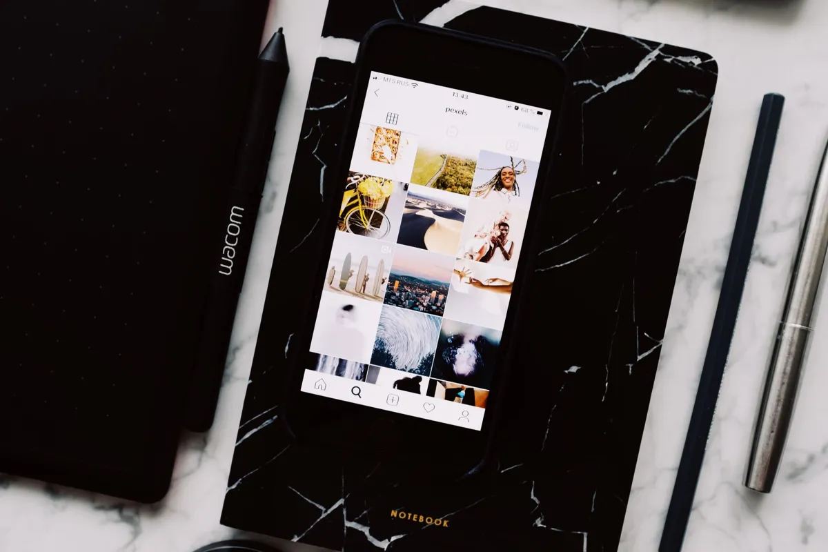 Phone showing a grid of photos beside a graphics tablet