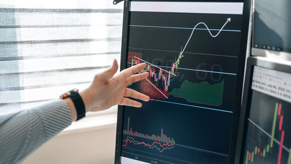 Hand pointing at data charts on a monitor