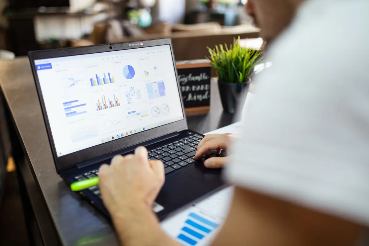 Spreadsheet data and charts being analysed on a laptop