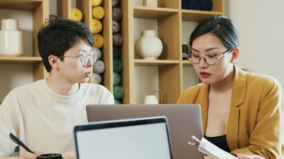 Two colleagues working together on a laptop in an office