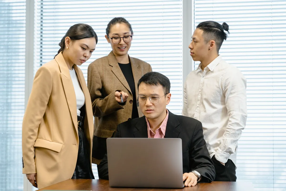 Colleagues discussing work around a laptop